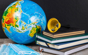 Глобус, книги, колокольчик и медицинские маски 