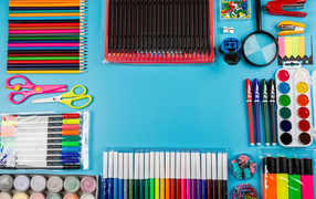 Много разноцветных канцелярских предметов на голубом фоне 