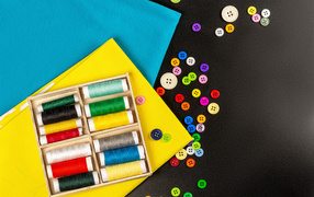 Разноцветные нитки, пуговицы и бумага на черном фоне 