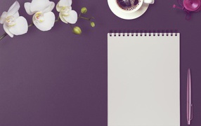 Блокнот с ручкой, цветами орхидеи и кофе на сиреневом фоне