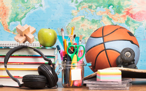 Школьные принадлежности на столе с наушниками и мячом 