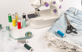 Швейная машинка,юбка и нитки на белом фоне 