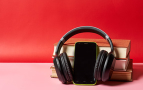 Смартфон, наушники и книги на красном фоне