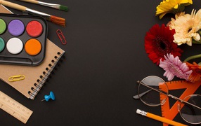 Канцелярские предметы, очки и герберы на черном фоне 