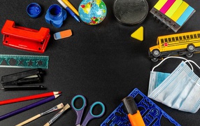 Канцелярские предметы, игрушки и маска на черном столе 