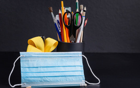 Канцелярские предметы на столе с медицинской маской