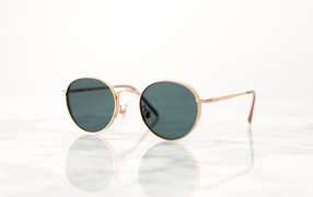 Солнечные очки лежат на зеркальной поверхности