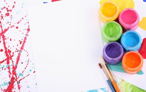 Белый лист бумаги с красками и кисточками