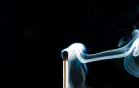 Белый дым от сожженной спички на черном фоне