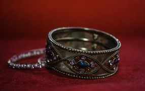 Красивый браслет с драгоценными камнями на красном фоне 