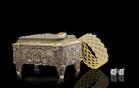 Шкатулка на черном фоне с золотыми украшениями 