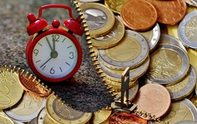 Euro coins with red alarm clock