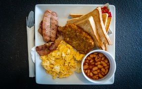 Завтрак на белой тарелке на черном столе 