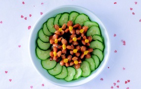 Огурцы с сосисками в тарелке на столе