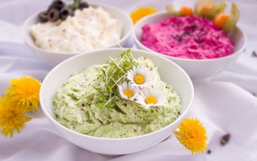 Вкусные салаты в белых мисках на столе с цветами