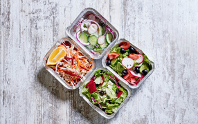 Разные овощные салаты в тарелках на сером столе 