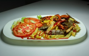 Картофель фри на тарелке с помидорами 