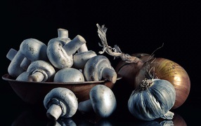 Fresh champignons with onions and garlic on a black background