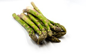 Свежая зеленая спаржа на белом столе