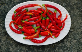 Острый красный перец чили на большой белой тарелке
