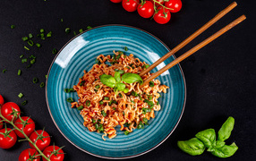 Макароны в соусе на столе с помидорами