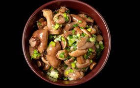 Маринованные маслята с зеленью в тарелке