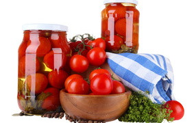 Маринованные помидоры в банках на столе со свежими