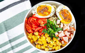 Каша в тарелке с помидорами, кукурузой, ветчиной и яйцом