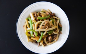 Салат с мясом в белой тарелке на черном фоне