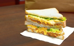 Сэндвич с сыром и листьями салата на столе