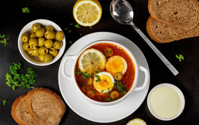 Солянка на столе  с хлебом и оливками 