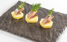 Три куска вареного картофеля с сельдью и укропом