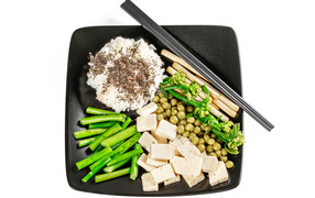 Овощи, сыр и рис на тарелке с палочками