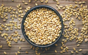 Зерна пшеницы в черной кружке на столе 