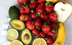 Avocado, strawberry, lemon and pear on gray table