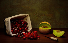 Корзина с черешнями на столе с дыней