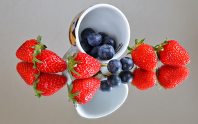 Чашка с ягодами черники и клубники на столе