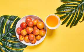 Вкусные спелые абрикосы с зелеными листьями на желтом фоне