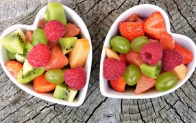 Салат из фруктов и ягод в белой тарелке на деревянном столе