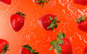 Красная клубника в воде на оранжевом фоне 