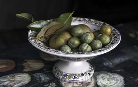 Белые сливы и зеленые яблоки в вазе на столе 