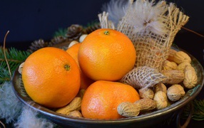 Желтые апельсины с арахисом  на тарелке