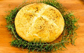 Loaf of fresh aromatic bread with rosemary on the table