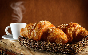 Two fresh croissants on the table with coffee
