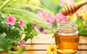 Банка ароматного меда на столе с цветами