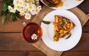 Кружка ромашкового чая на столе с куском пирога