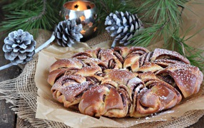 Сдобный венок с вареньем на столе с шишками