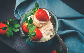 Сливочное мороженое с ягодами клубники в чашке с ложкой