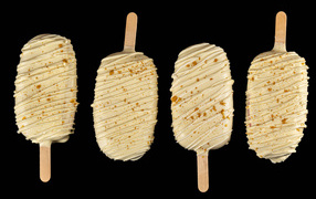 Мороженое на палочке в белом шоколаде на черном фоне