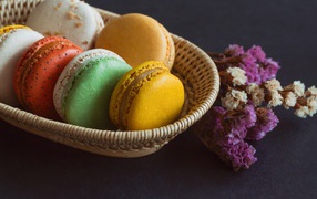 Разноцветный десерт макарон в корзинке на столе с цветами
